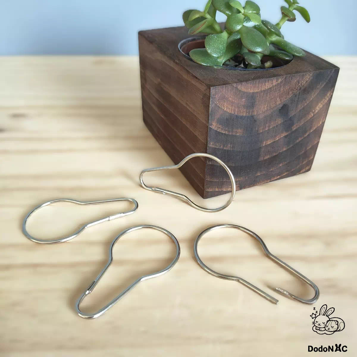 Crochet d'attache pour hamac dodoNAC - Système d'attache pour hamac à œillet présenté sur fond bois