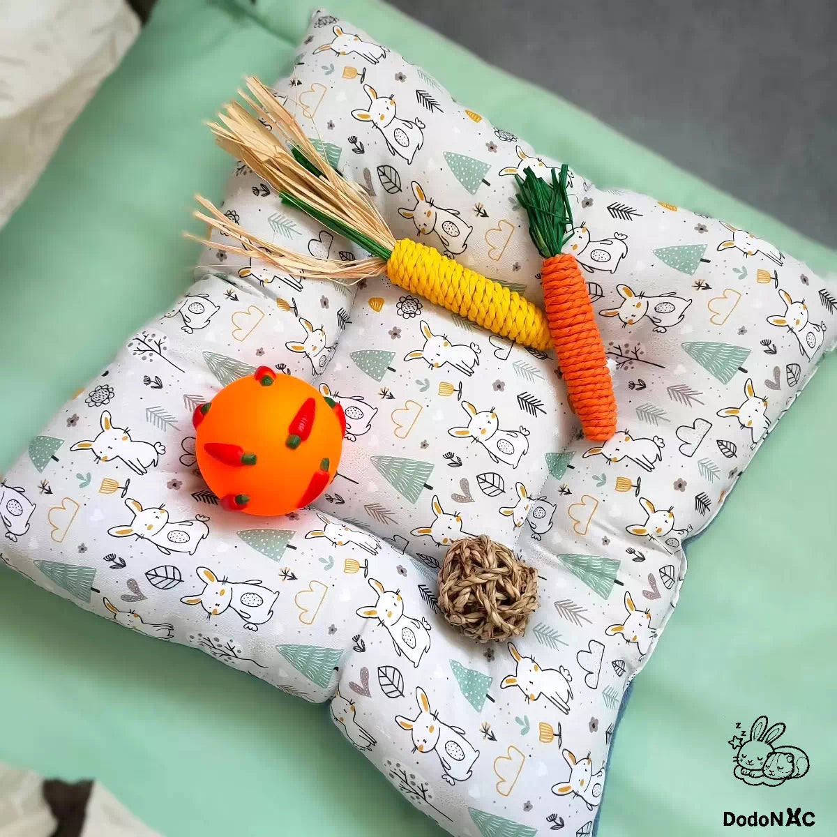 coussin moelleux dodoNAC (40x40cm) lit pour lapin, furert, cochon d'inde et petits animaux confortable et rembouré sur un tapis avec des jouet et accessoires posé dessus