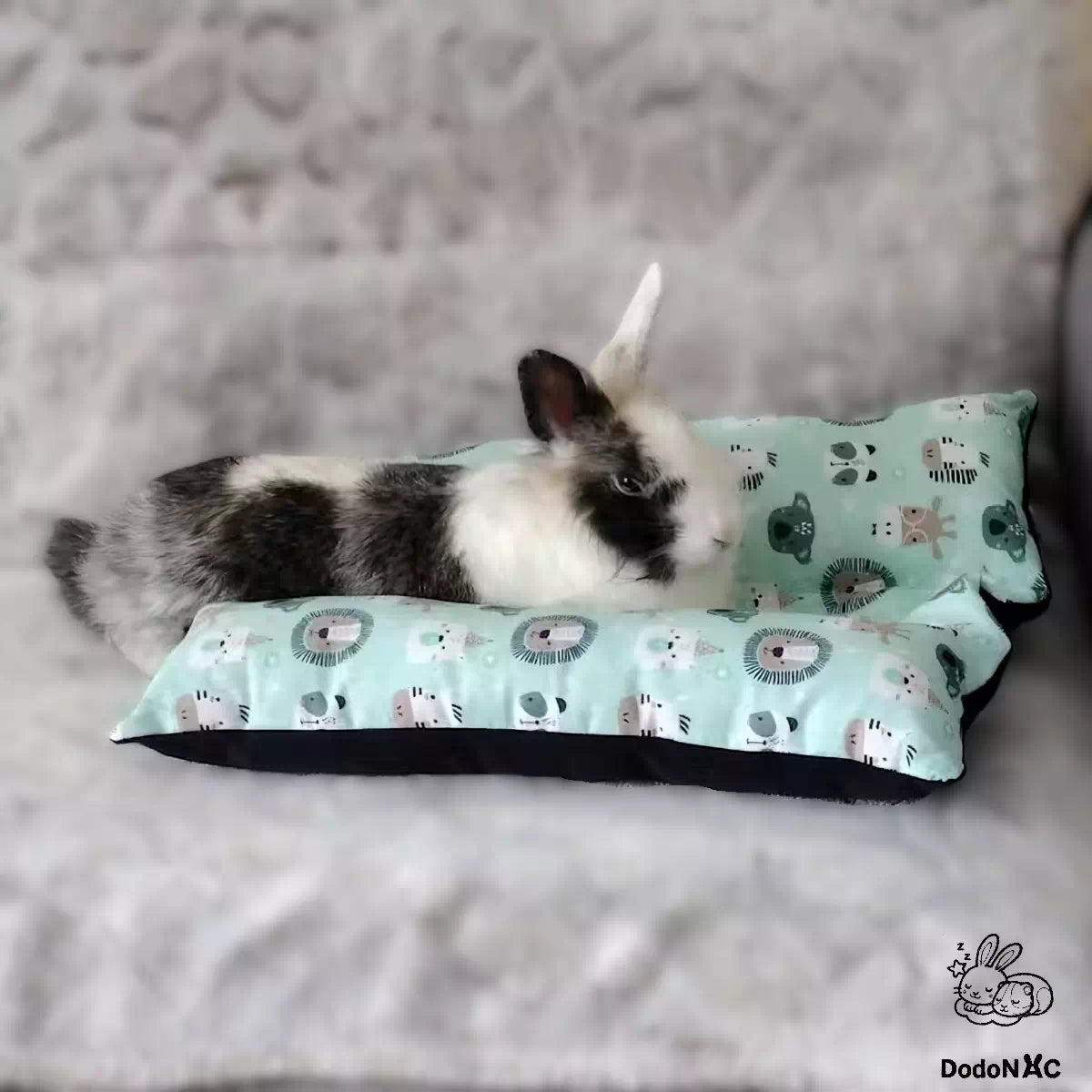 lapin mignon blanc et noire couché sur son snugabun, snuggle bed, accessoire lapin, coussin absorbant lapin dodoNAC