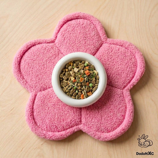 Tapis absorbant et tapis de gamelle en forme de fleur rose pour cochon d'Inde, avec une écuelle remplie au centre.