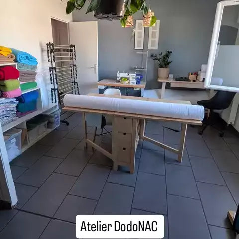 L'atelier de couture DodoNAC à Romorantin-Lanthenay avec sa table de coupe, ses tissus polaires colorés et sa machine à coudre.
