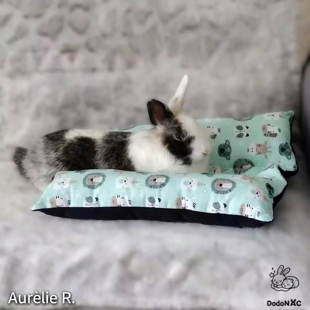 lapin mignon blanc et noire couché sur son snugabun, snuggle bed, accessoire lapin, coussin absorbant lapin dodoNAC